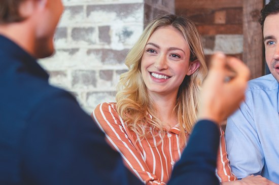 Stock image of a young couple meeting with a mortgage loan officer to discuss buying a new home