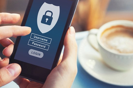 Stock photo of a cell phone displaying the log in screen and a cup of coffee