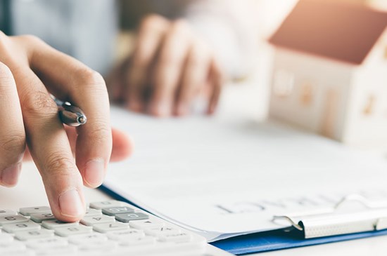 Stock image of a hand typing on a calculator, calculating the rate difference to make a refinance make sense.