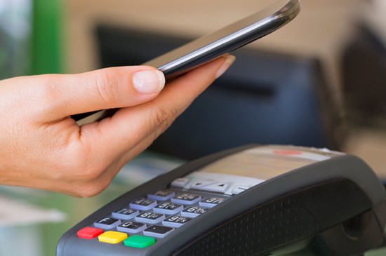 Stock photo of someone using a mobile device to pay with a digital wallet.