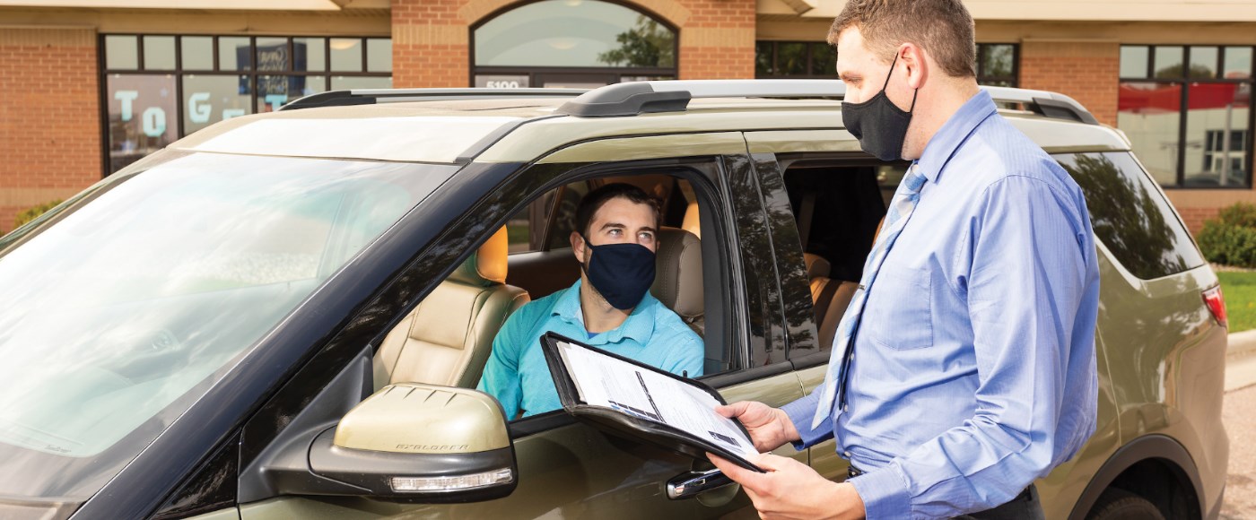 Great Western Bank employee delivering documents to a customer's car during the pandemic.