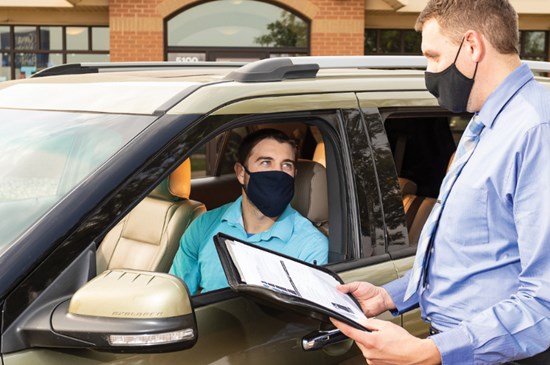 Great Western Bank employee delivering documents to a customer's car during the pandemic.