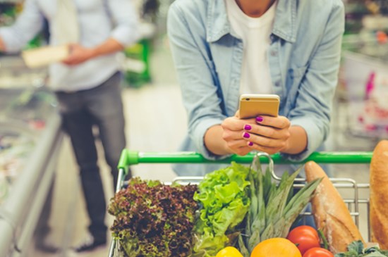 A female grocery shopper checks her phone