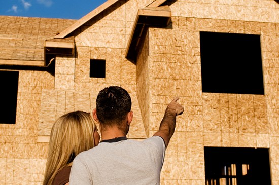 Stock photo of a couple observing a home under construction