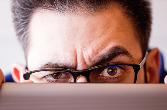 Man peering over the top of a computer.