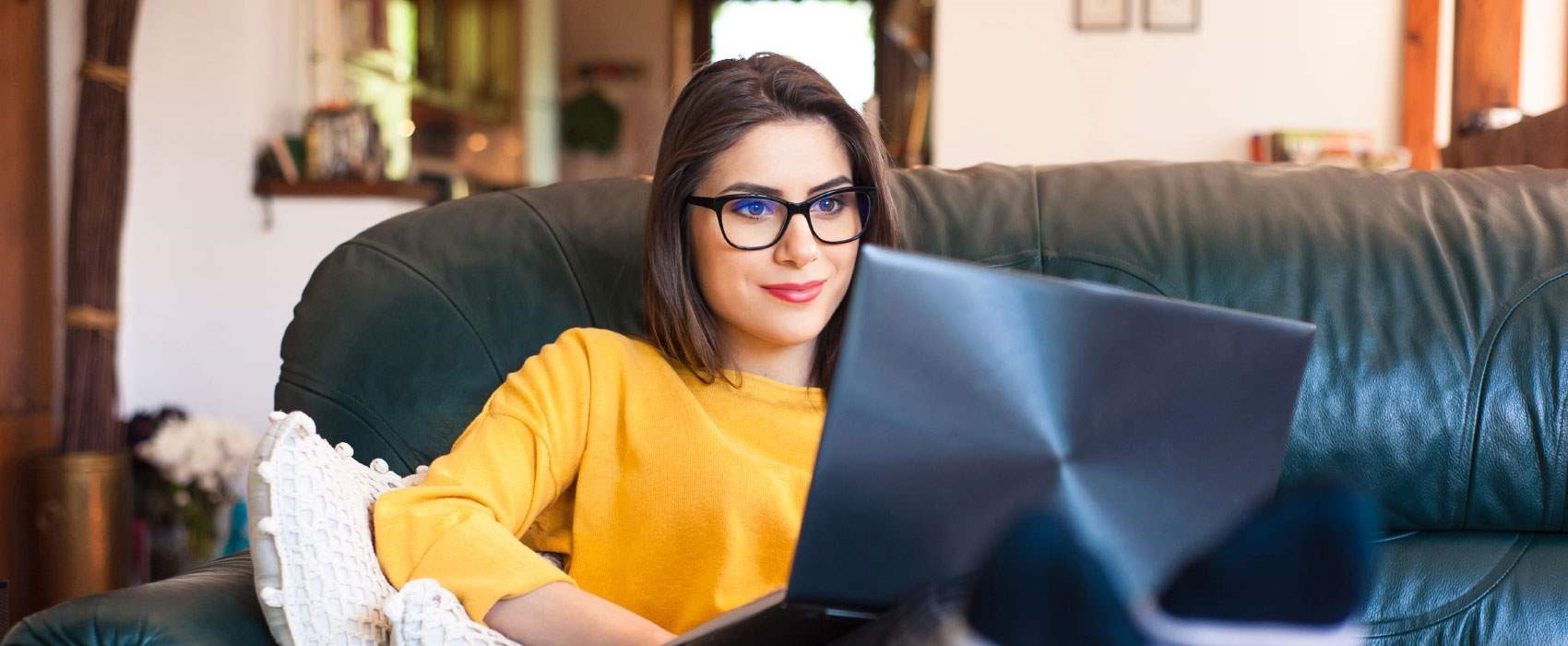 Young woman sitting at her laptop choosing a checking account to open online from Great Western Bank.