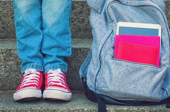Stock photo of a student sitting on the steps with a backpack