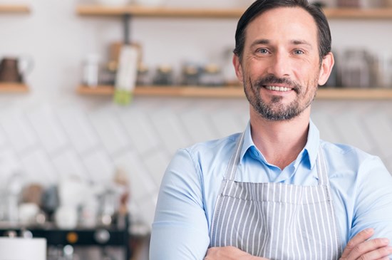 Stock image of a small business owner posing in his coffee shop