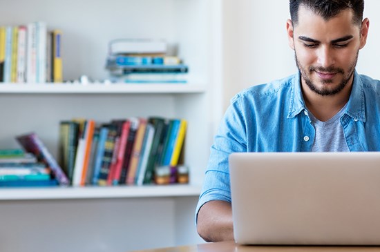 Stock image of a young man at his laptop conducting online banking.