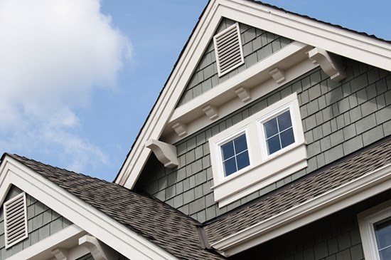 Stock image of a roof peak on a new house with a blue sky in the background.
