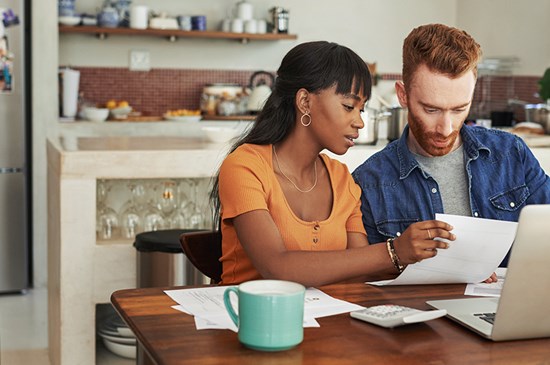 Image of  a young couple researching financing options at a laptop. 