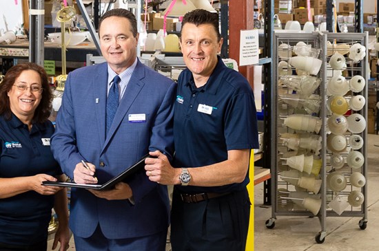 Leadership from Pikes Peak Habitat for Humanity and a business banker from Great Western Bank pose for a photograph together inside a warehouse.