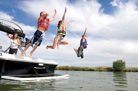 Kids jumping off a boat into a lake