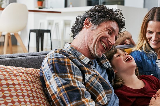 Stock image of a family laughing on a couch